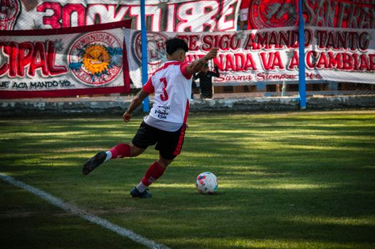 A soccer player in action kicking the ball on a field in Mendoza, Argentina.