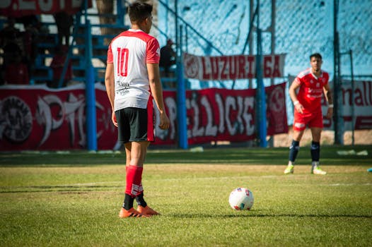 Soccer players on the field in Mendoza, Argentina, prepared for a competitive match under bright sunlight.