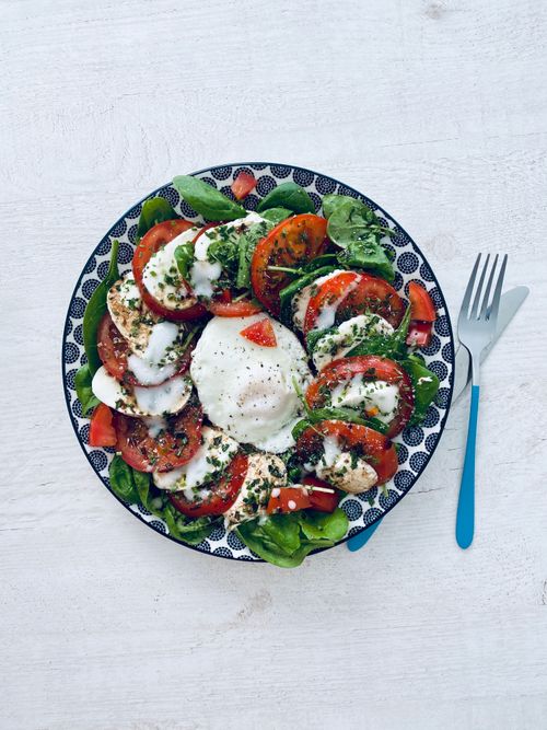Free A vibrant Caprese salad with tomatoes, mozzarella, and basil on a decorative plate. Stock Photo