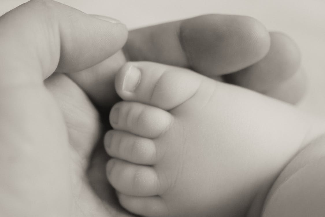 Grayscale Photography Person Holding Baby's Foot