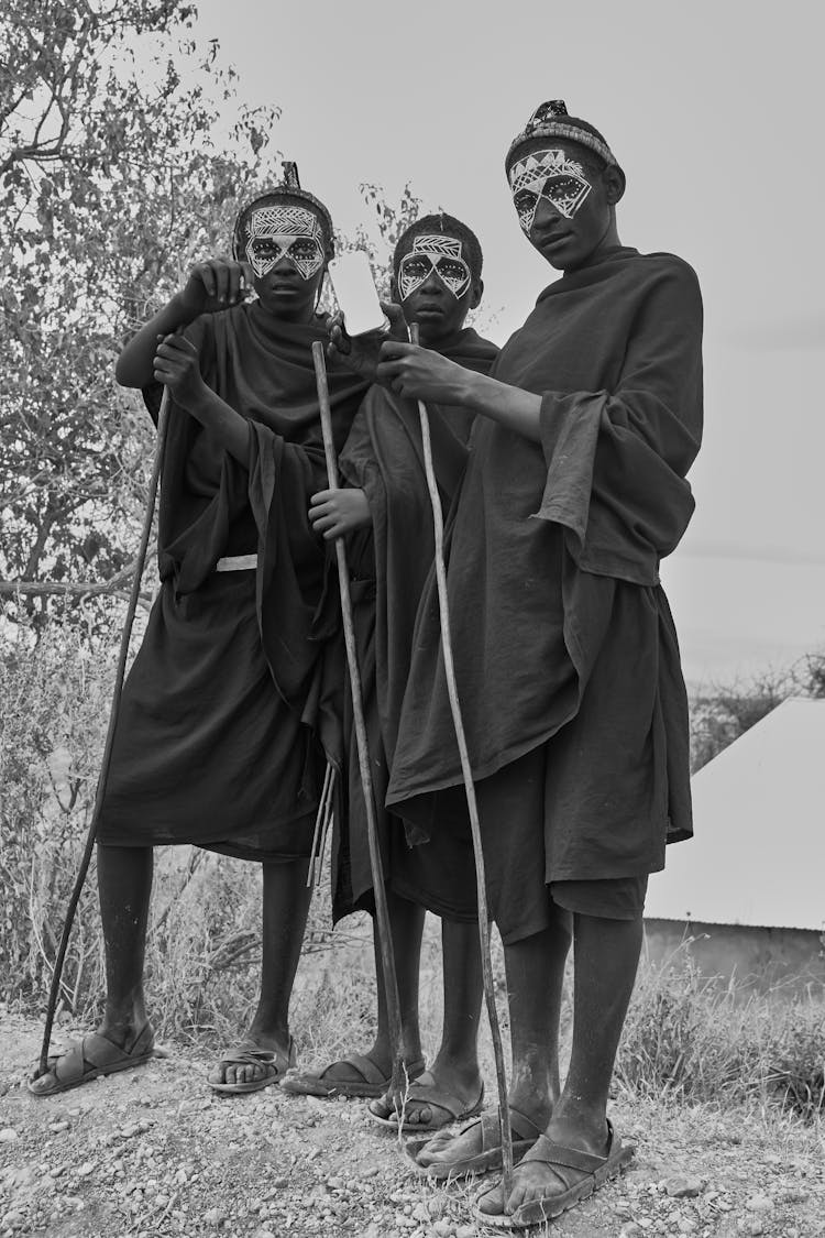 Grayscale Photo Of People Holding Sticks