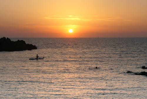 Silhouette of Person Riding on Boat during Sunset