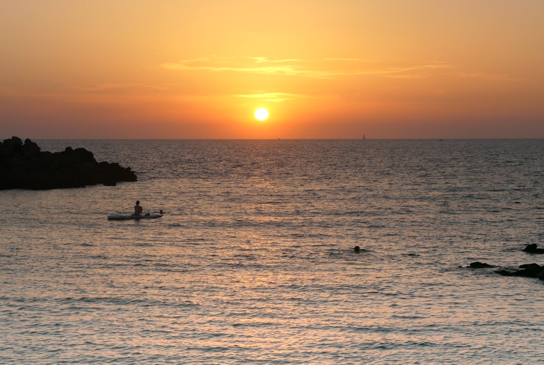 Silhouette of Person Riding on Boat during Sunset