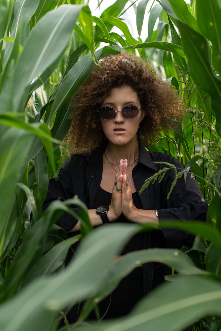 Woman With Clasped Hands Among Corn Leaves