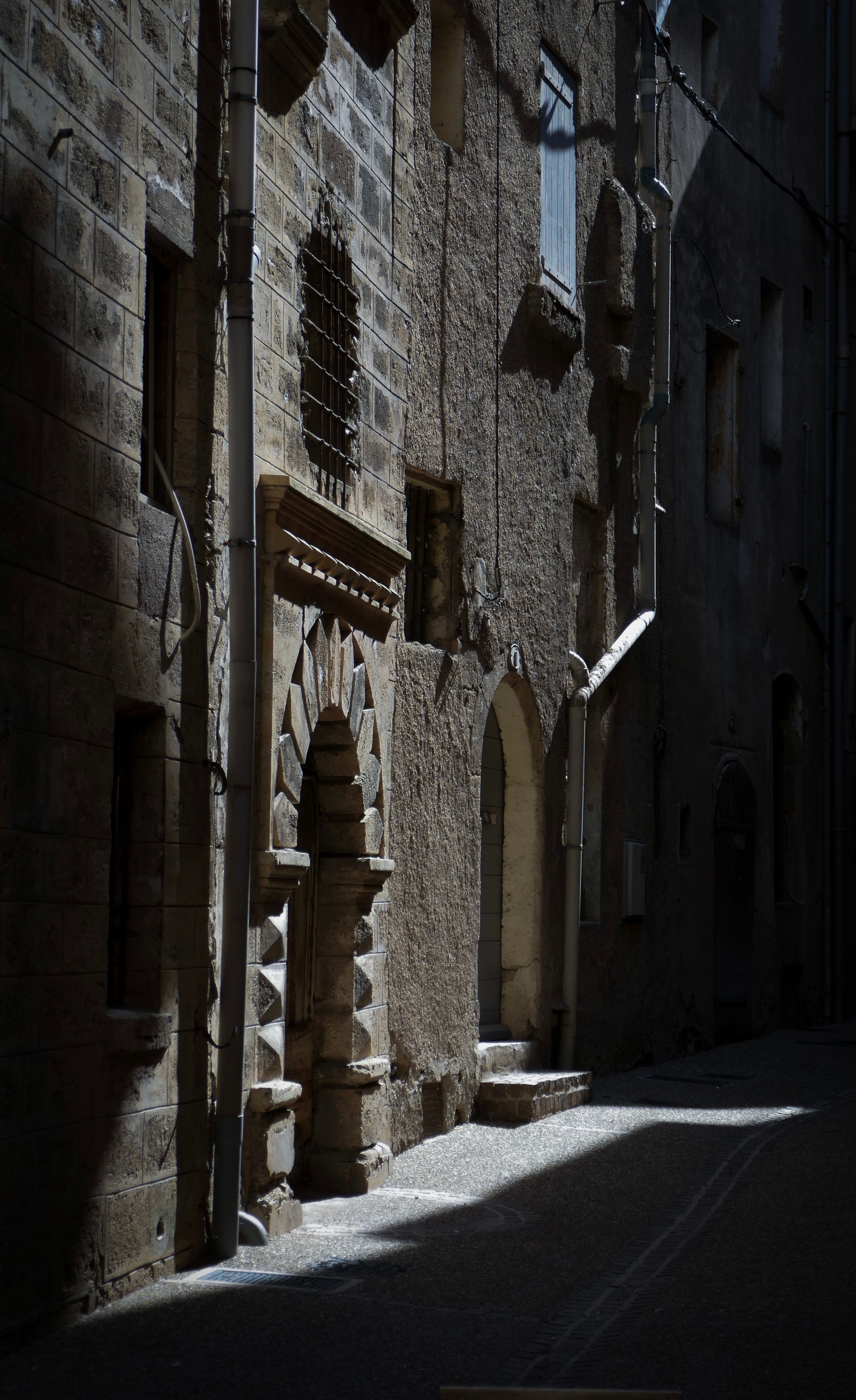 A narrow alley with historic stone architecture and arches illuminated by sunlight