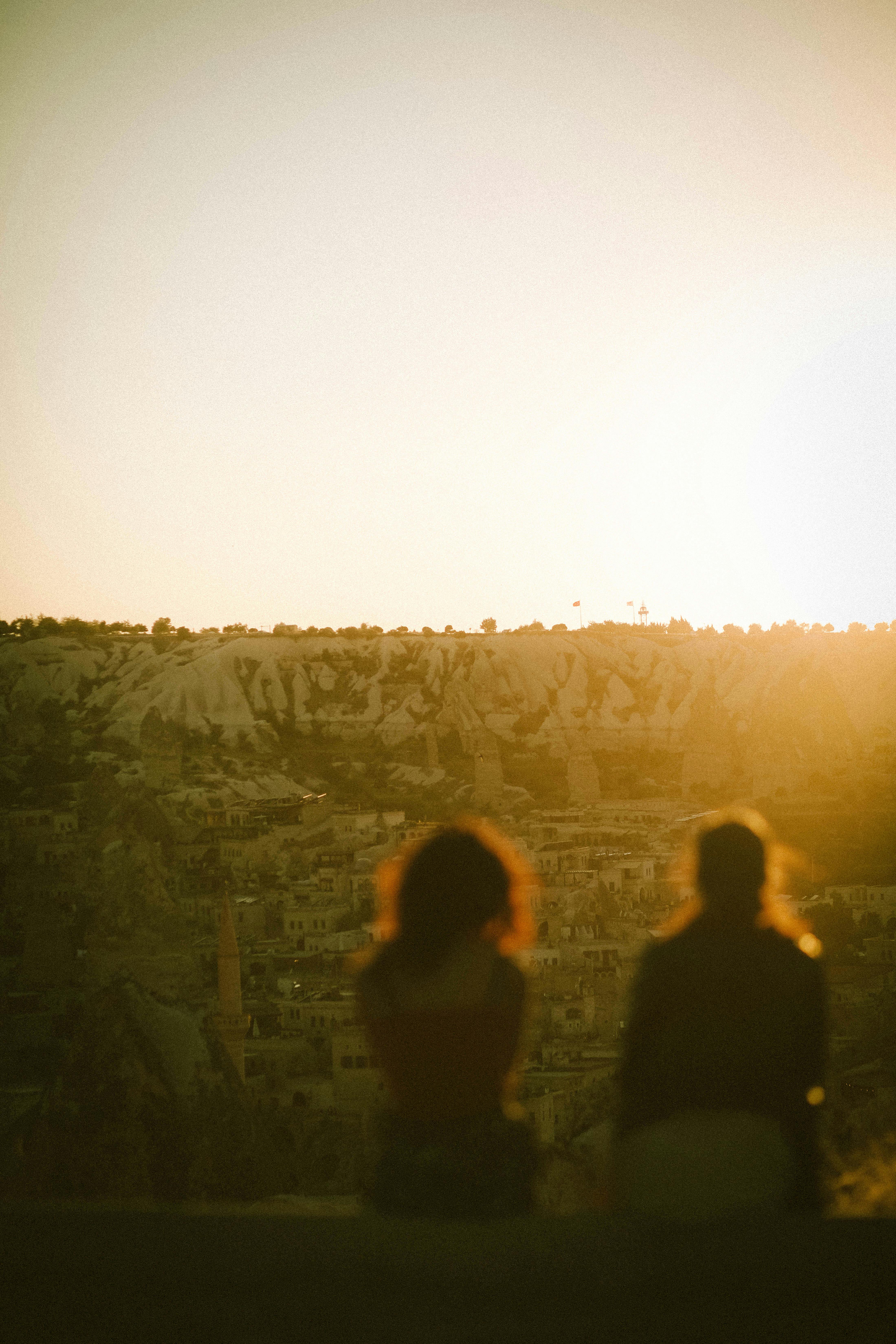 Silhouettes of two people overlooking Göreme's landscape at sunset, Turkey.