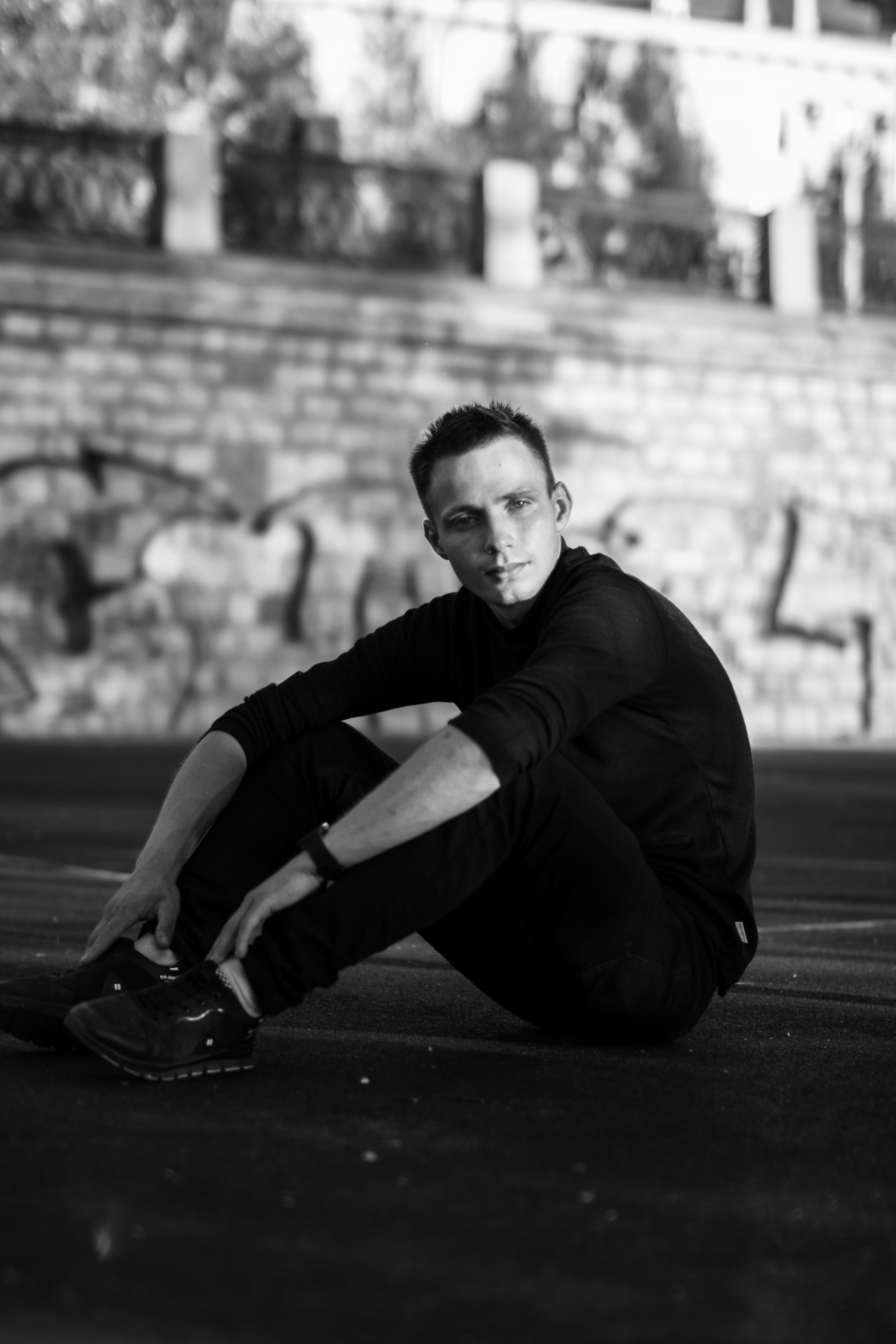 Black and white photo of a man sitting in a thoughtful pose outdoors.
