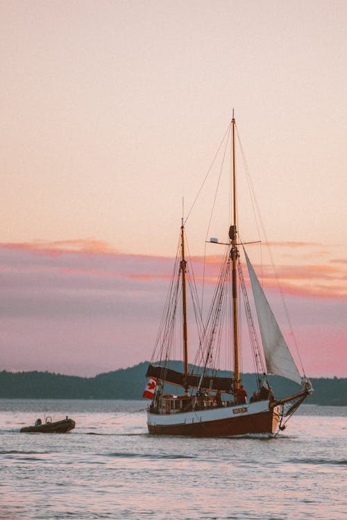 Free Ships with Sails Towing Motorboat Stock Photo