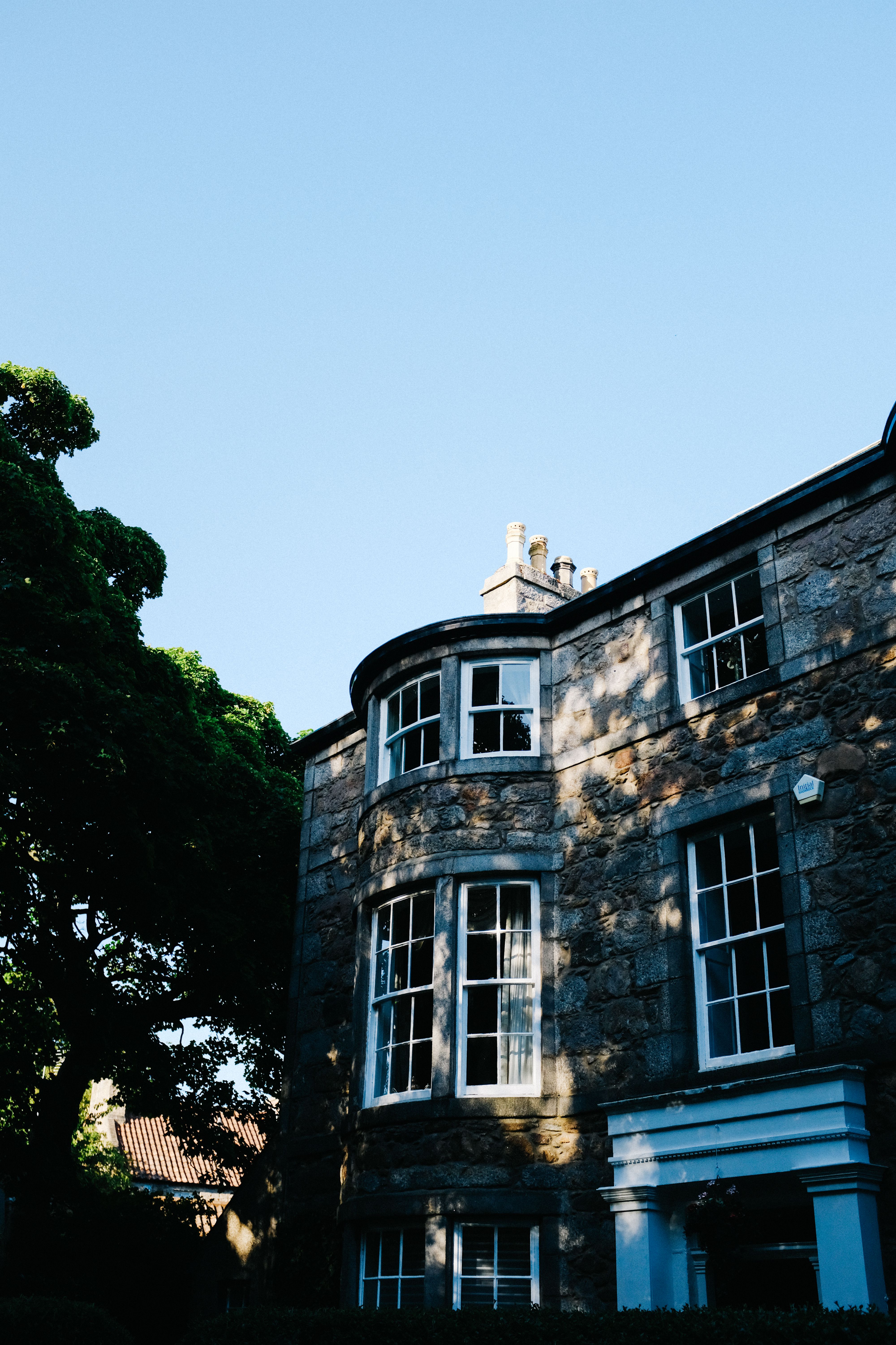 A Cobblestone House Near Green Tree Under Blue Sky · Free Stock Photo
