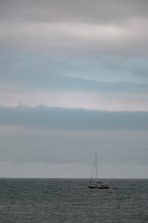 Sailboat Sailing at Sea under a Cloudy Sky