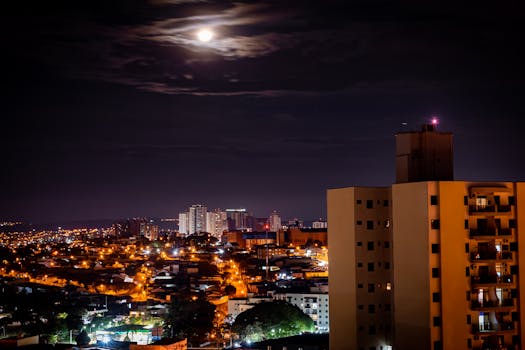 Stunning aerial view of Campinas city at night, illuminated under a full moon.