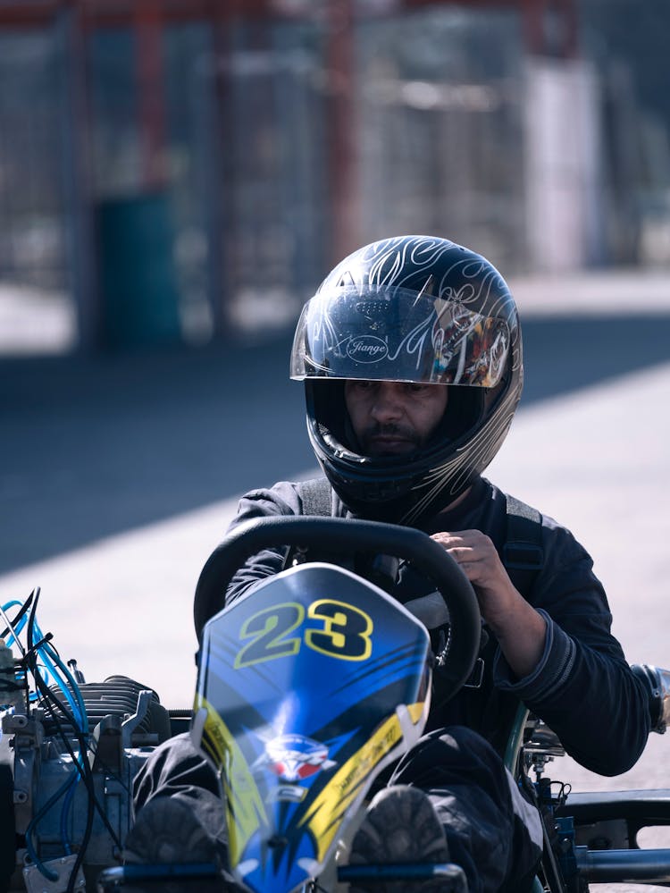 A Man In Black Helmet Riding On A Go Kart