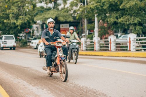 Free Motorcyclists ride along a bustling street in Siem Reap, Cambodia, showcasing local transportation. Stock Photo