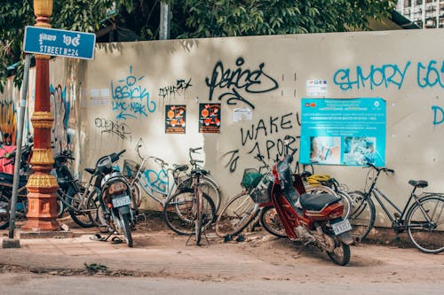 Biciclette E Moto Parcheggiate Di Fronte Al Muro Con Graffiti