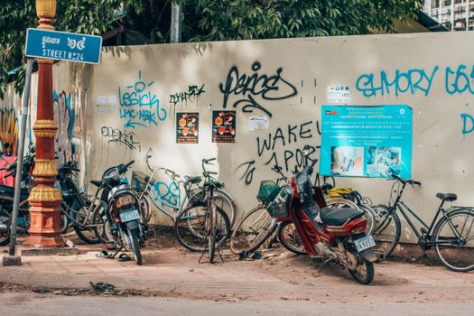 Bicycles And Motorcycle Parked In Front Of Wall With Graffiti