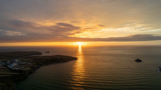 A breathtaking sunset view along the Cornwall coastline with a vibrant sky reflecting on the ocean.