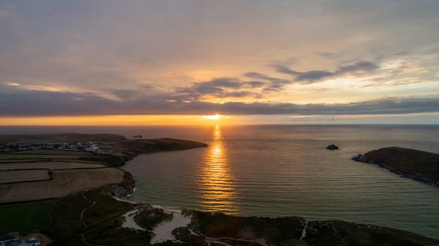 A captivating aerial view of Cornwall's coastline at sunset with beautiful ocean reflections.