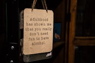 一块复古风格的木制招牌，上面印着滑稽的酒水报价，用绳子悬挂在室内