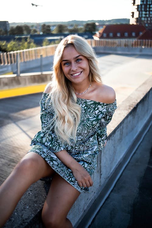 Woman in Printed Dress Sitting on Concrete Railing