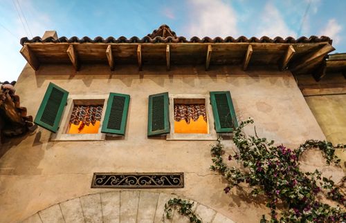 Free Charming traditional house facade with green shutters and warm window lighting. Stock Photo