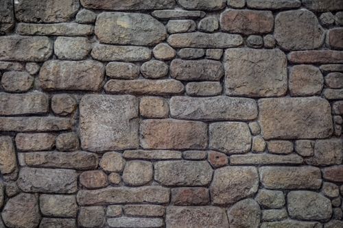 Free A detailed view of an antique stone wall with varied shapes and textures. Stock Photo