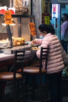 Woman wearing a mask preparing Mexican street food at a market stall during the pandemic.
