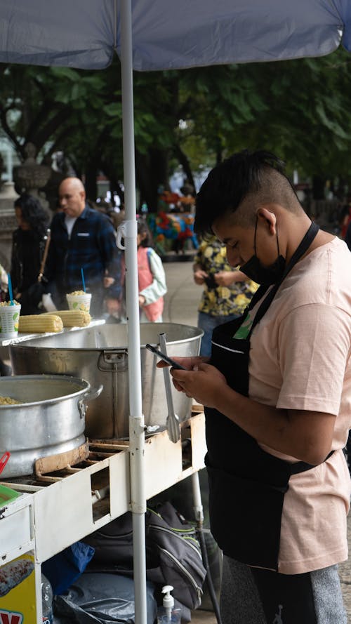 Man Using Phone at Street Food Cart
