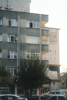 Vertical shot of urban residential buildings with cars and trees, captured at sunset.