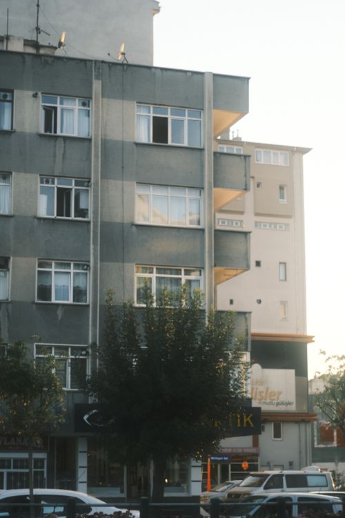 Free Vertical shot of urban residential buildings with cars and trees, captured at sunset. Stock Photo