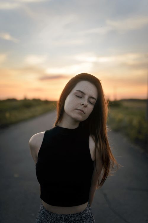 Free Portrait of a woman with eyes closed outdoors during sunset, conveying tranquility. Stock Photo