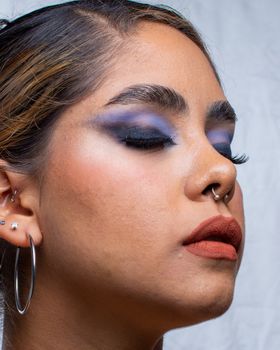 Stylish woman with bold makeup and piercings, eyes closed, Ciudad de México.