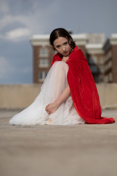 Free A young woman in a red cloak sits on a rooftop in Orlando, Florida. Stock Photo