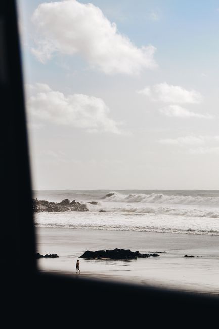 A lone person walks on a quiet beach in Porto, Portugal, under a cloudy sky. Perfect for peaceful and travel themes.