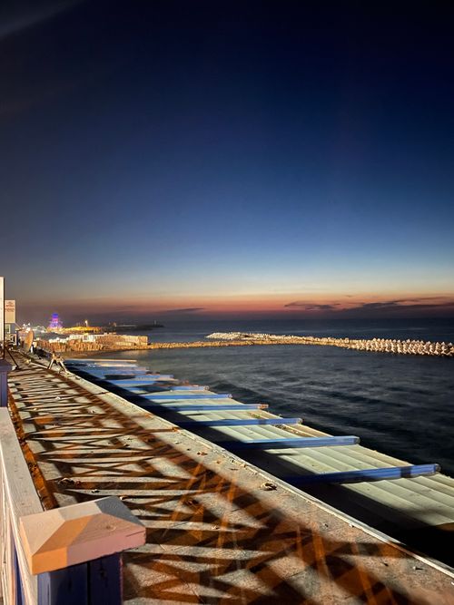 Free Captivating sunset over a calm sea with beautiful sky hues and harbor structures. Stock Photo