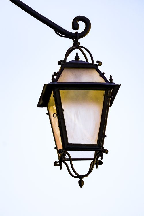 Free Close-up of an ornate, vintage street lamp set against a clear sky. Ideal for architectural themes. Stock Photo