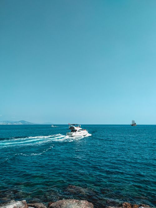 Free A yacht glides through the calm, expansive ocean under a clear blue sky, exuding tranquility. Stock Photo