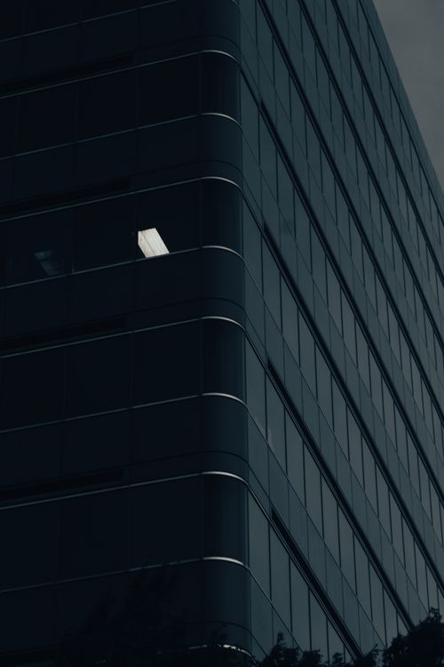 Free Low angle view of a modern glass building facade in urban setting, featuring unique architectural design. Stock Photo