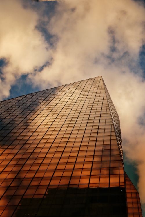 Free Dramatic low angle shot of a glass skyscraper in New York against a cloudy sky. Stock Photo