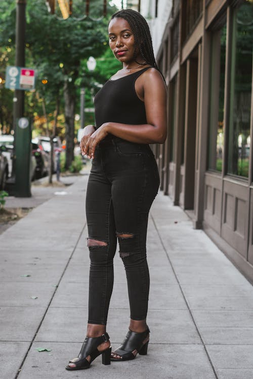 Free Woman in Black Tank Top and Black Leggings Standing on Sidewalk Stock Photo