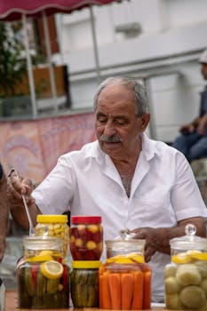 Senior man serving pickles at outdoor market in Istanbul, Turkey. Authentic ethnic food scene.