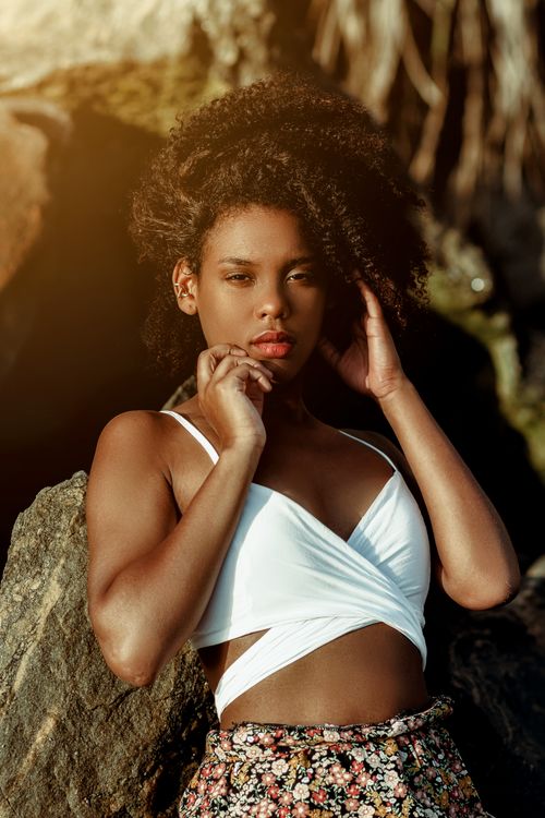Free A stylish woman with afro hair posing elegantly outdoors in natural lighting. Stock Photo