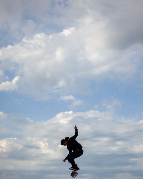 Free Dynamic shot of a skateboarder performing a jump trick against a backdrop of a cloudy sky. Stock Photo