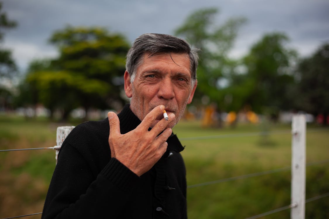 Man Wearing Black Long Sleeves Smoking a Cigarette
