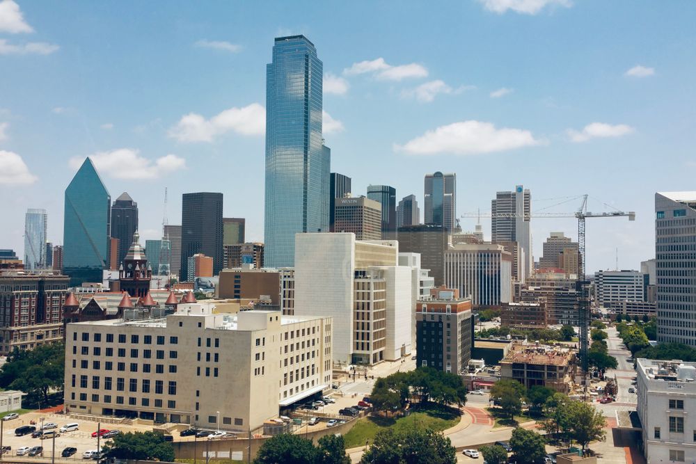 Aerial view of Dallas skyline featuring modern skyscrapers under a clear blue sky.