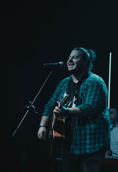 Male singer passionately performs with guitar on stage in Mendoza, Argentina.