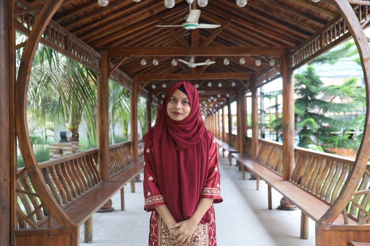 Woman In Traditional Clothes And Abaya In Wooden Gazebo