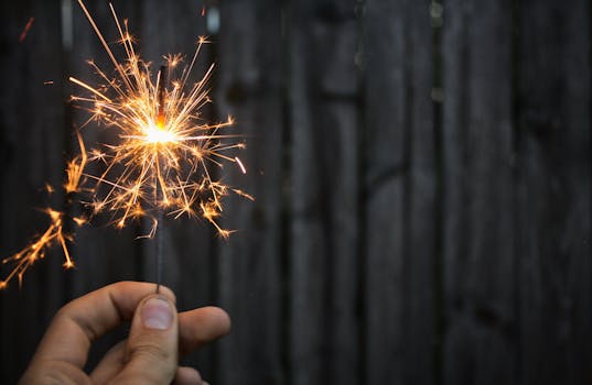 黑暗中，一个人手持烟火，明亮的火花营造出节日氛围