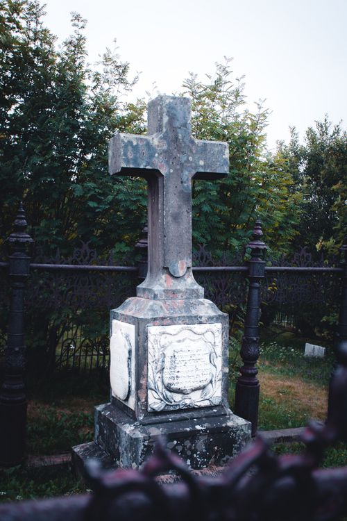 Free A weathered stone cross in a tranquil, historic cemetery setting. Stock Photo