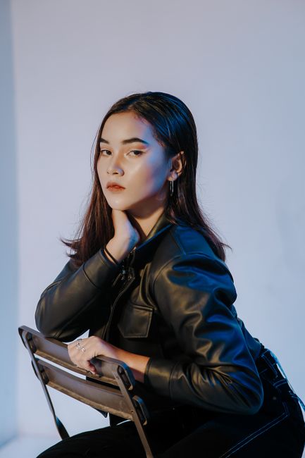 Stylish portrait of a woman posing in black leather jacket against a white background.