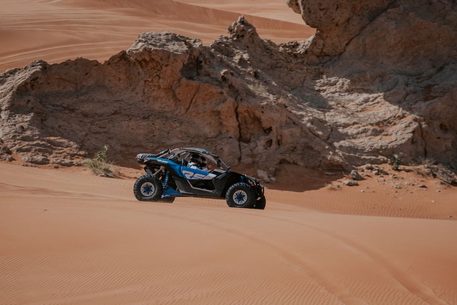 Explore the thrill of off-road ATV driving through stunning desert dunes with rocky backgrounds.